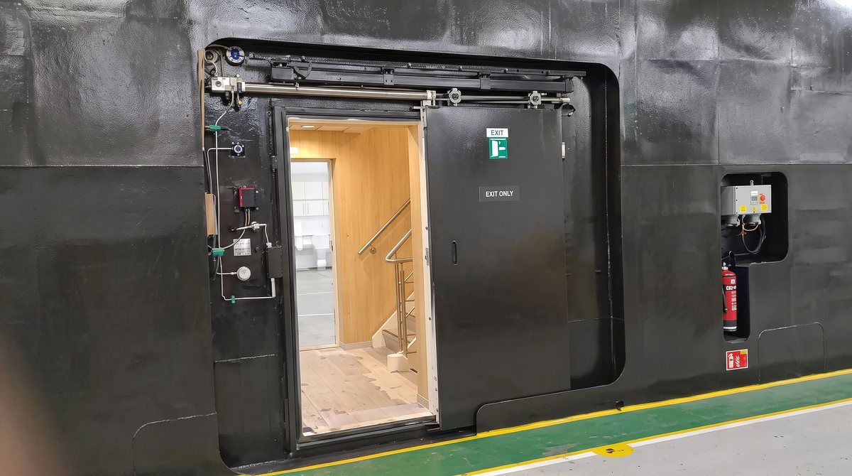 Power-driven marine door installed in a vessel compartment